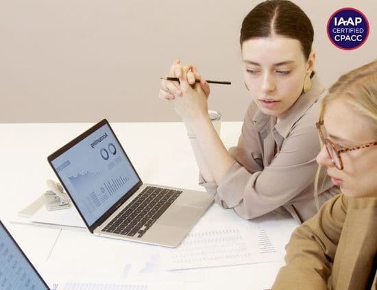IAAP-certified auditors reviewing accessibility data on laptops with a CPACC certification badge